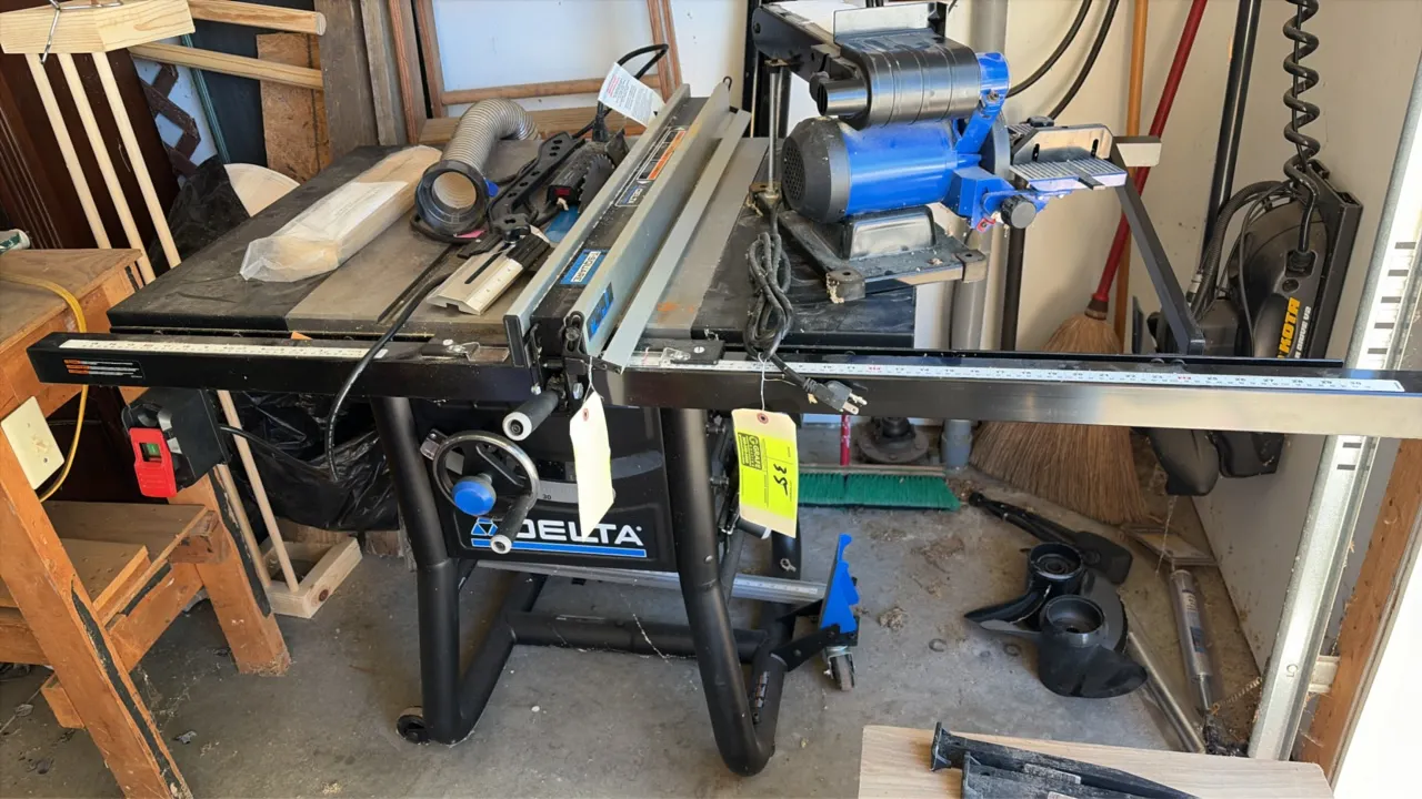 Delta table saw. Features a T-Square rip fence system, front handwheel adjustment controls, and integrated power switch. Mounted on a tubular steel mo