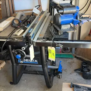 Delta table saw. Features a T-Square rip fence system, front handwheel adjustment controls, and integrated power switch. Mounted on a tubular steel mo