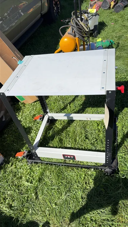 JET portable metal work table. Features adjustable-height legs and side adjustment knob. Mounted on a mobile base with casters and foot locks. Dimensi