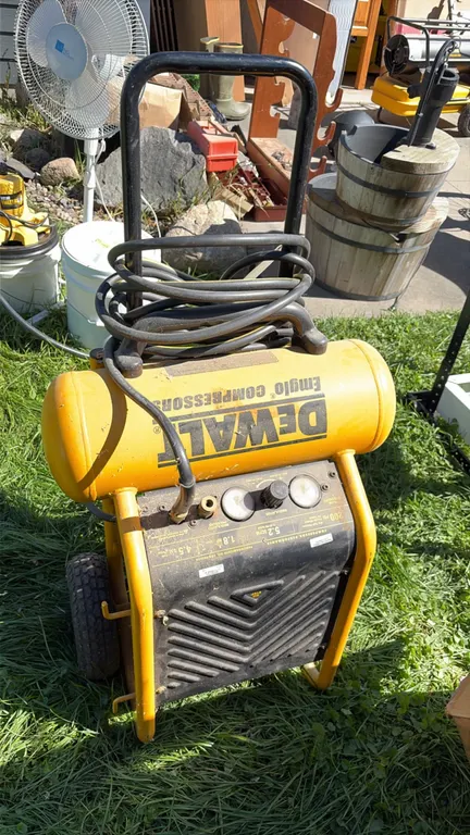 DeWalt Emglo portable air compressor. Features 4.5-gallon tank, 200 PSI max pressure, 1.8 HP motor, and 5.2 SCFM at 90 PSI. Equipped with dual pressur