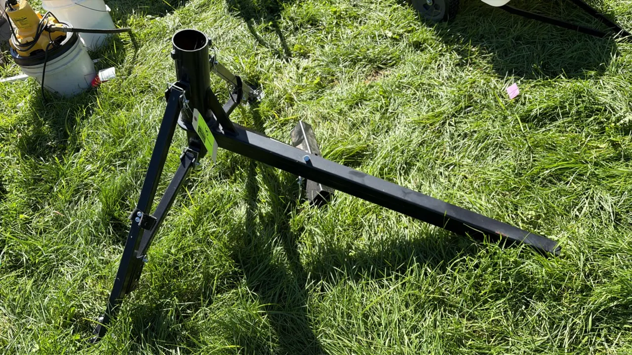 Adjustable metal tripod bracket stand. Features black painted steel construction, central vertical tube receiver, and folding support legs with foot p