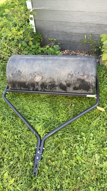 Agri-Fab tow-behind lawn roller. Features black poly drum with fill plug, tubular steel frame, integrated scraper bar, and hitch bracket. 36"W.