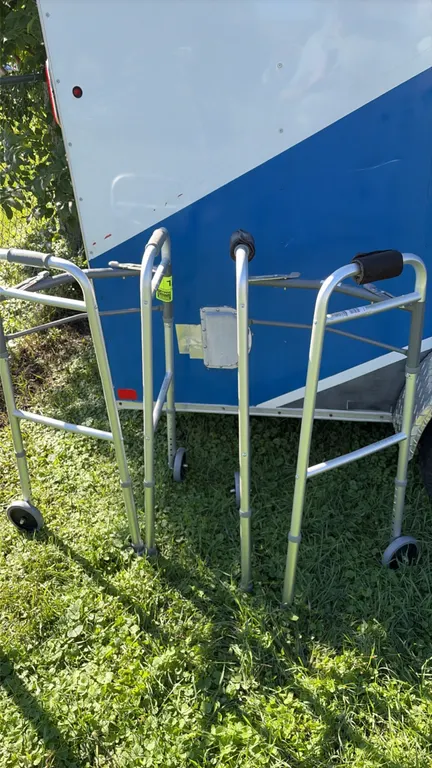 Adjustable folding walker. Features aluminum frame construction, dual front wheels, rear glide tips, padded hand grips, and push-button adjustable hei