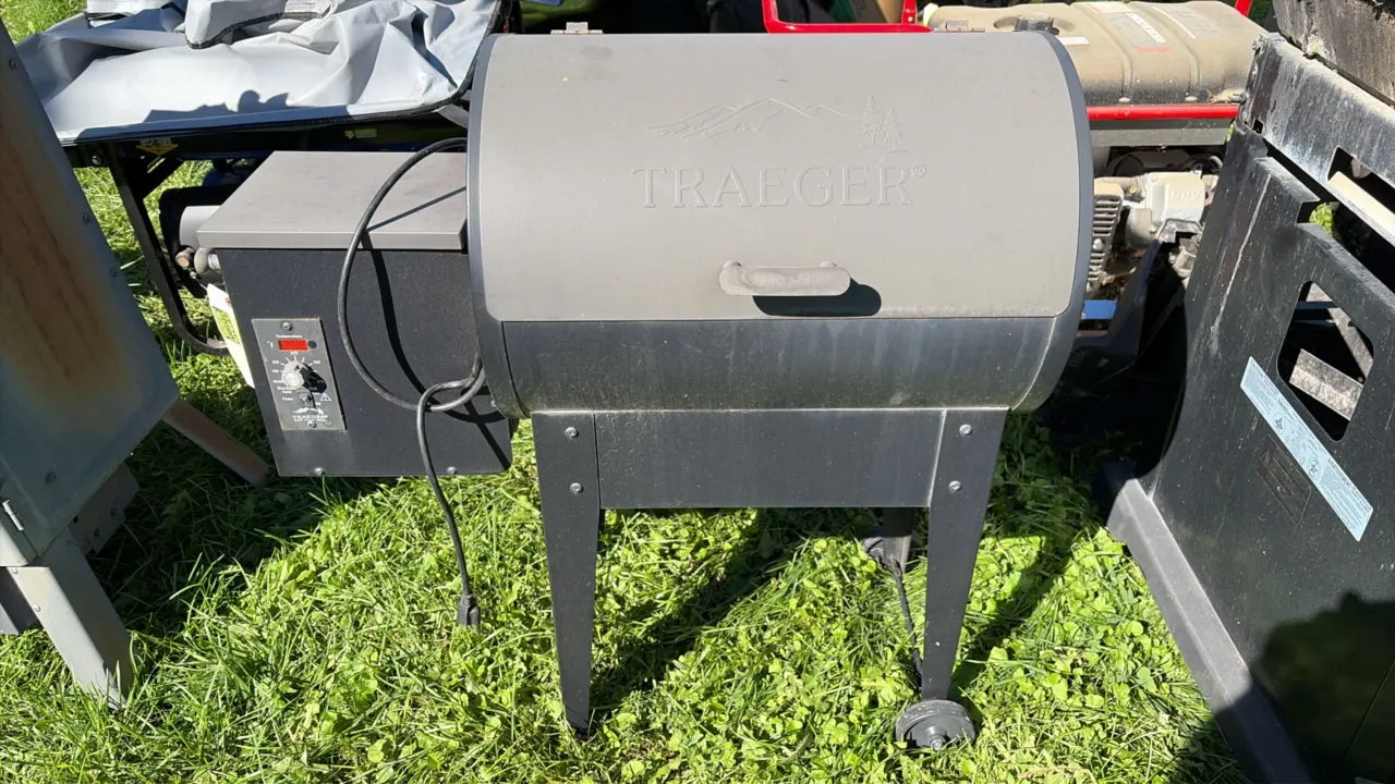 Traeger wood pellet smoker grill. Features side pellet hopper with safety grate, digital temperature control panel with LED readout, and wire cooking