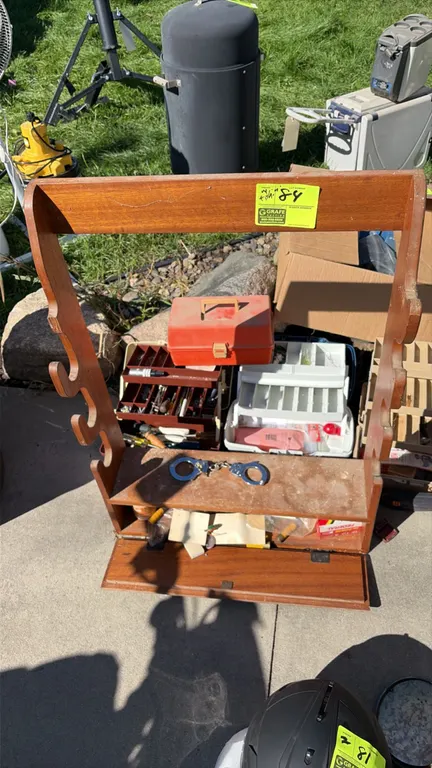 Sporting and outdoor goods package lot. Includes 3-place wood gun rack with bottom storage compartment, handcuffs, assorted shotgun shells, (5) tackle