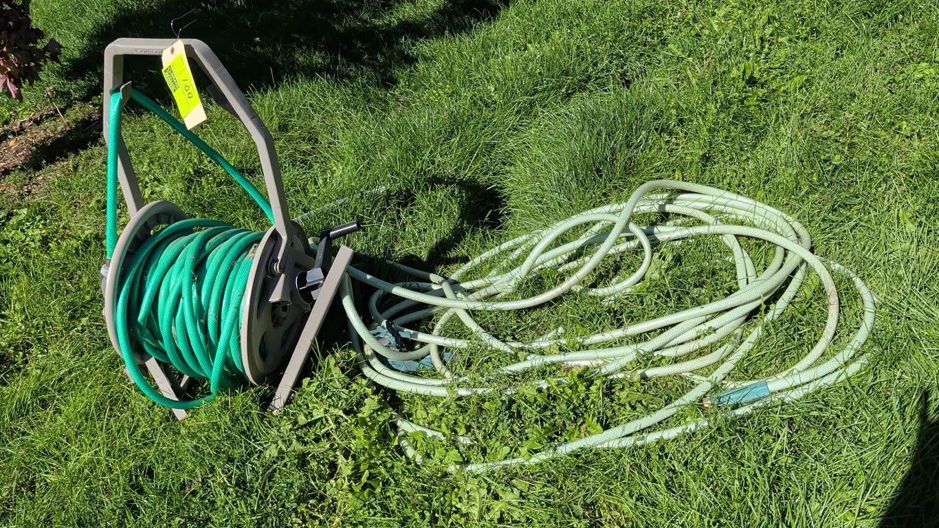 Suncast hose reel with garden hoses. Features molded plastic frame with manual crank handle. Includes garden hoses. Note: Hose reel is broken.