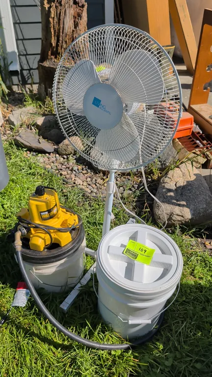 Utility lot including a Living Accents pedestal floor fan, a Wayne water pump with hose attachment, and (2) plastic buckets with twist-off lids.