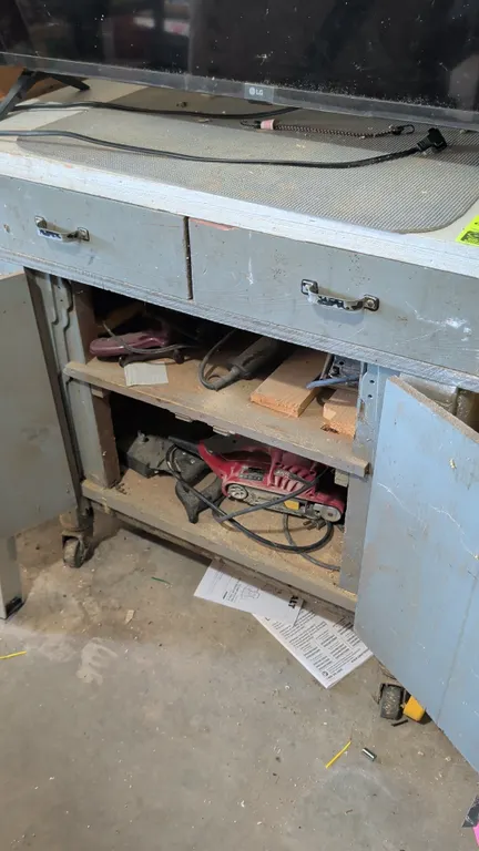 Wooden mobile cabinet with contents. Includes electric sanders featuring Skil belt sander, hand saws, assorted sandpaper, jigsaw blades, and drill bit