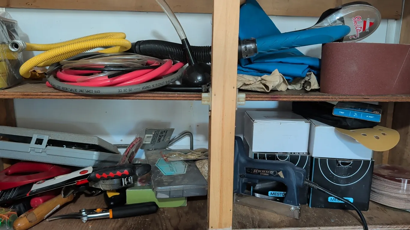Assorted workbench and cabinet contents. Includes Arrow ETF50BN electric stapler, hand tools, sanding paper and sanding belts, assorted fasteners, hos