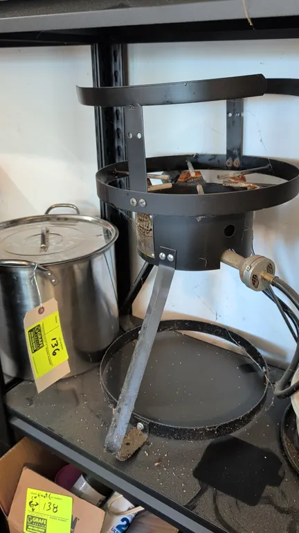 LP gas outdoor cooker with stainless steel stock pot and lid. Includes gas hose and regulator. Features steel frame stand with upper pot support ring