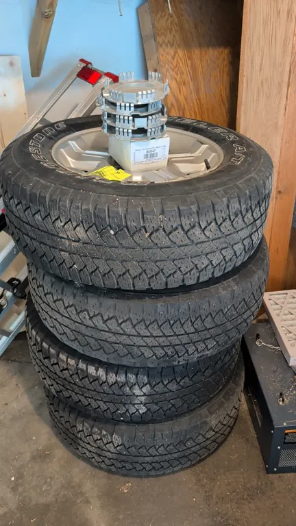 Bridgestone Dueler A/T P265/65R18 tires mounted on 6-lug silver alloy wheels. Features 112S load and speed rating, tubeless radial construction, and M