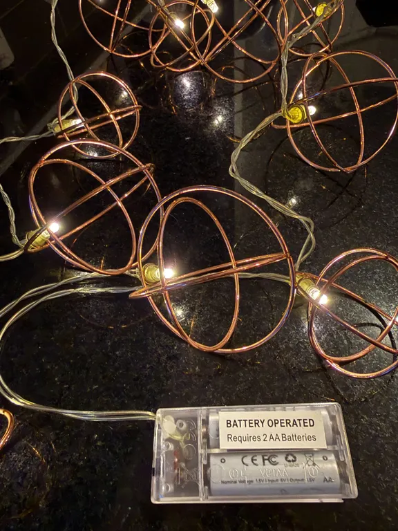 Battery-operated decorative string lights warm white LED bulbs enclosed in geometric copper-colored