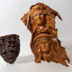HANDCRAFTED LEATHER WALL HANGING AND TERRA COTTA MASK PIECE.