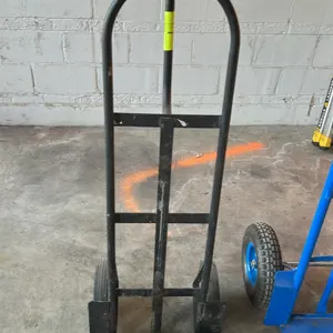 Metal 2-wheel hand truck. Features a tubular metal frame, loop handle, integrated wheel guards, and (2) solid rubber tires. Additional hand trucks and