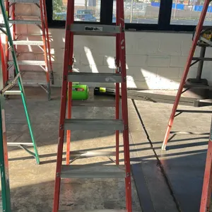 Louisville 6' stepladder. Features orange fiberglass rails, aluminum steps, and a molded top cap. Note: Background ladders and equipment not included.