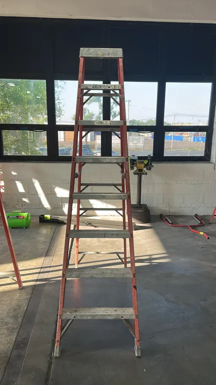 Louisville 8' fiberglass stepladder. Features orange fiberglass rails, aluminum steps, metal top cap, and folding spreader braces. 8'H.