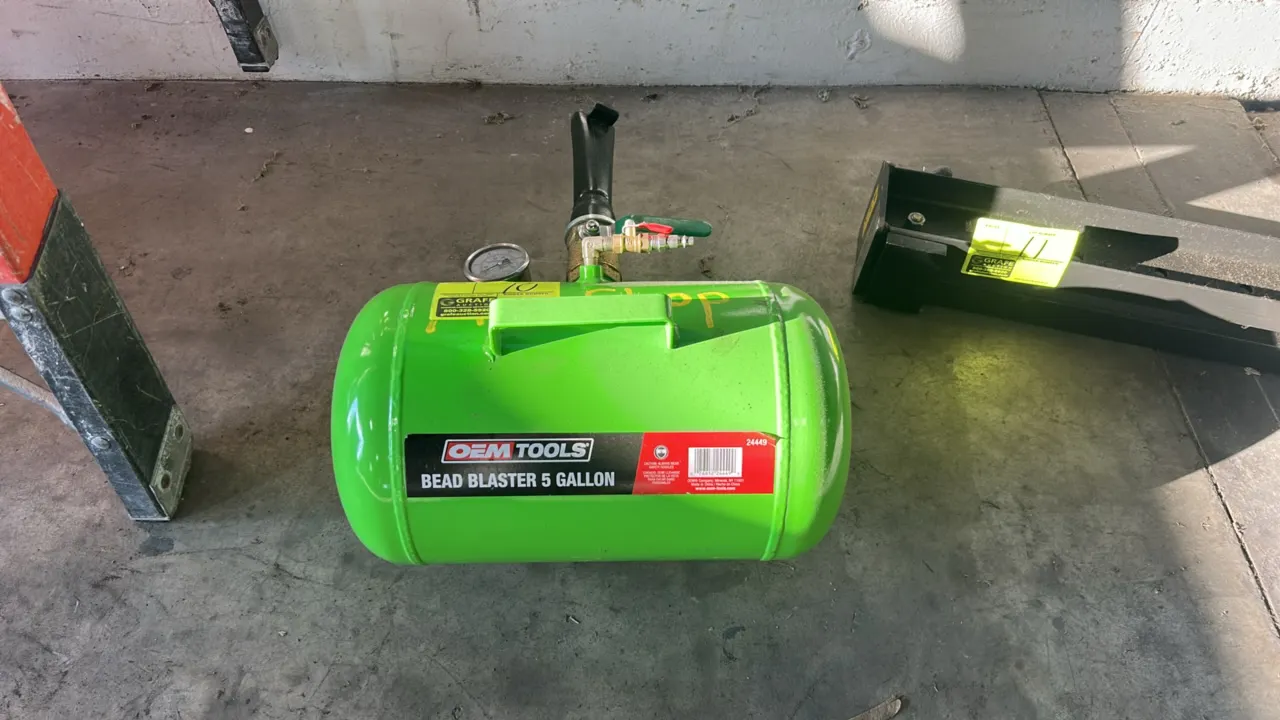 OEMTOOLS 24449 5-gallon tire bead seater. Features a steel air storage tank, integrated carry handle, pressure gauge, ball discharge valve with barrel