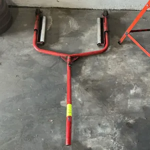 Truck tire and wheel dolly. Features red tubular steel frame construction, dual rotating steel roller assemblies, two wheels, and an extended leverage
