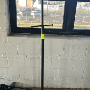 Underhoist support jack stand. Features threaded screw rod with T-handle adjustment, contoured top saddle, and circular steel base. Floor jack and bac