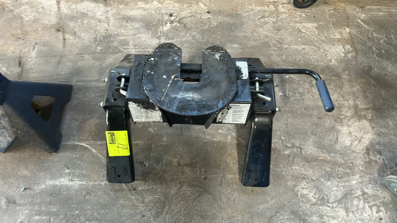 Fifth-wheel trailer hitch. Features pivoting hitch head, dual support legs with quick-release mounting pins, and side-mounted release handle with grip