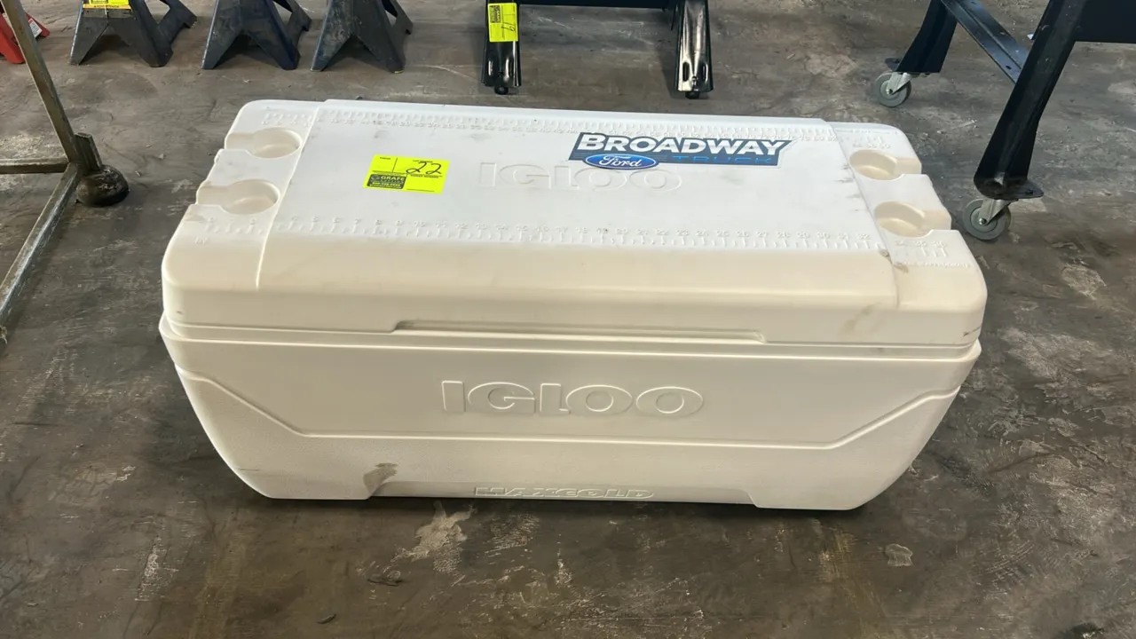 Igloo MaxCold cooler. Features white plastic construction, molded cup holders, integrated lid ruler, side swing-up carry handles, and drain plug. 3'L.