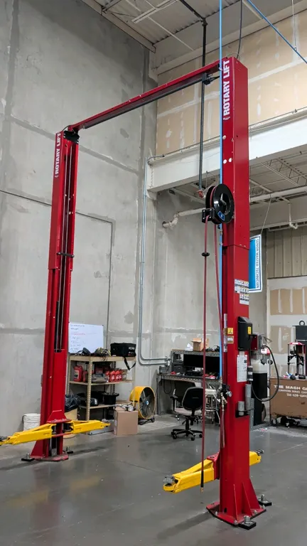 Rotary Lift SP012N7T8 two-post automotive lift. Features 12,000 lb capacity, overhead crossbeam, swing arms, hydraulic power unit, and an attached Gra