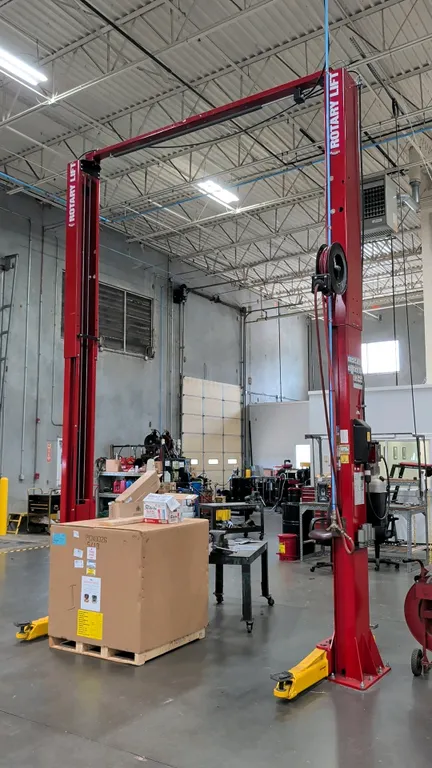 Rotary Lift SPO12N7T8 two-post automotive lift. Features 12,000 lb capacity, overhead beam configuration, symmetric arms, and a Graco retractable hose