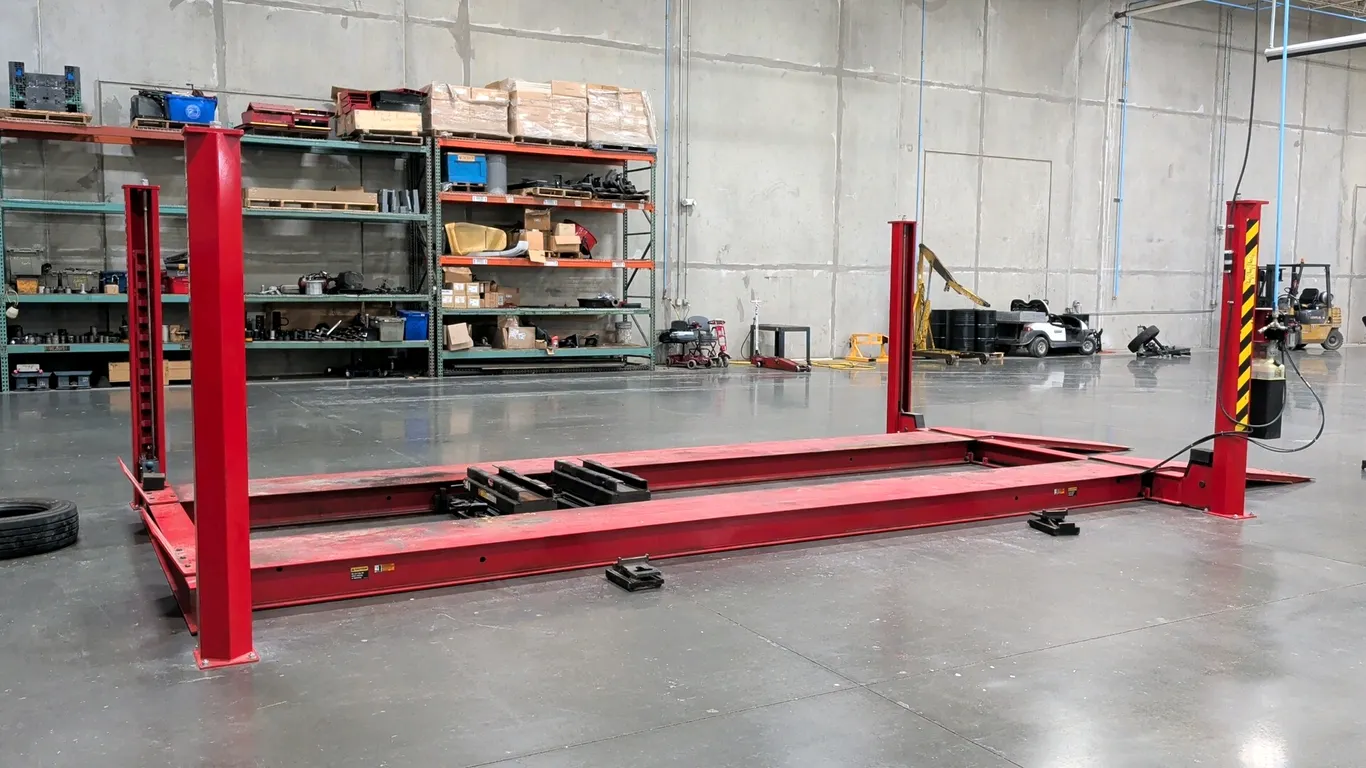 Rotary SM30N010 four-post drive-on vehicle lift. Features 30,000 lb capacity, drive-on runways with approach ramps, dual rolling bridge jacks, and an