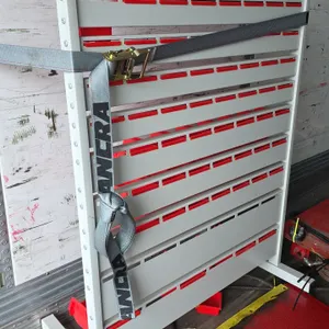 Metal workpiece storage rack. Features multi-tier slotted rail panels with assorted red plastic hanging bins. Free-standing steel frame with leveling 