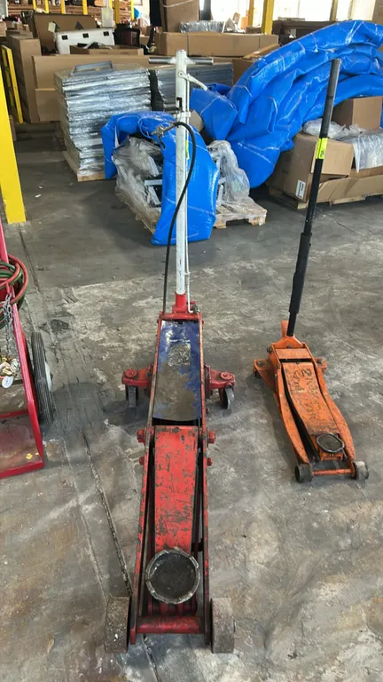 10-ton commercial hydraulic floor jack. Features long-chassis steel frame, T-handle with release control, pneumatic air valve assembly, front steel ro