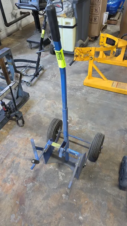 OTC 5017A brake drum dolly. Features adjustable drum cradle, control handle, and rubberized top hand grip. Mounted on two pneumatic tires.