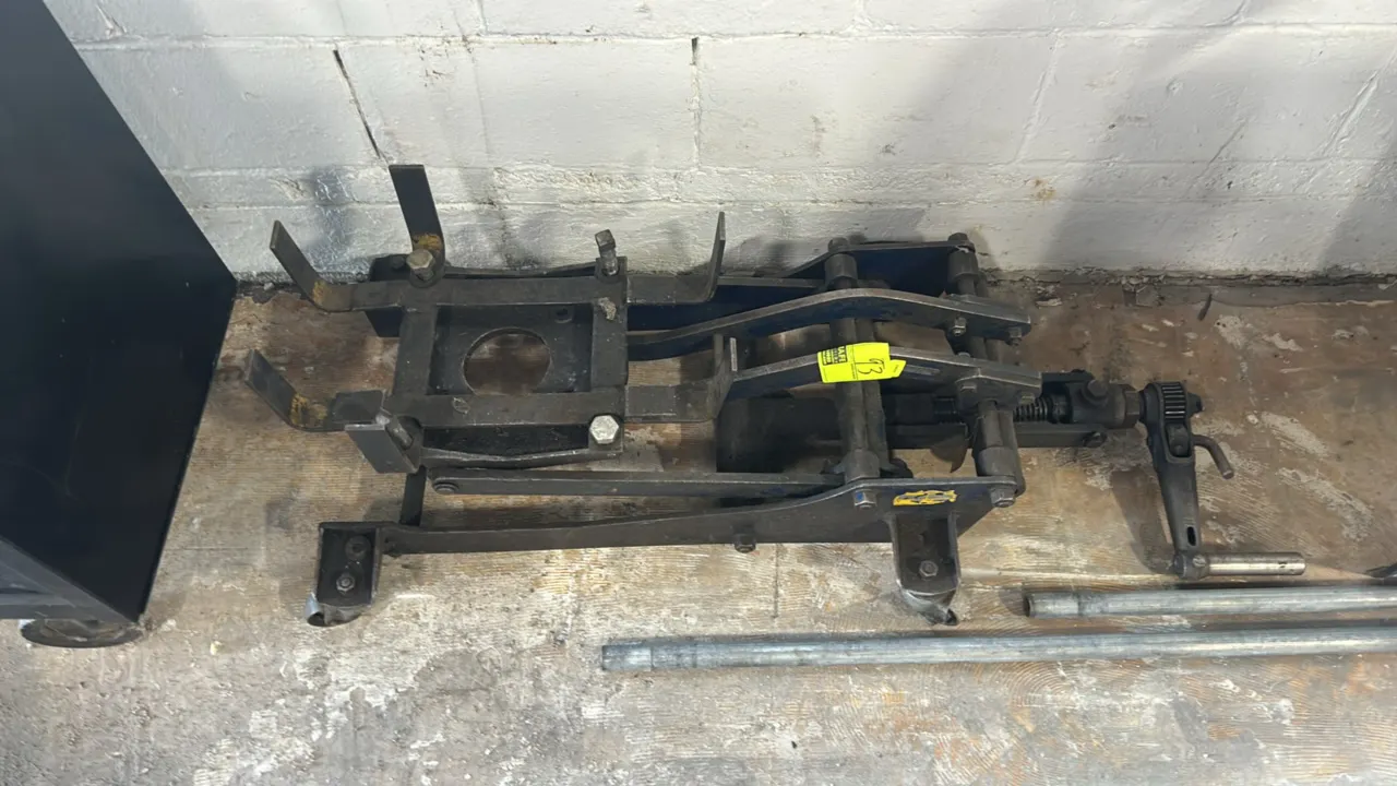 Manual low-profile transmission jack. Features mechanical screw-drive operation with ratchet crank handle, adjustable saddle cradle with support brack