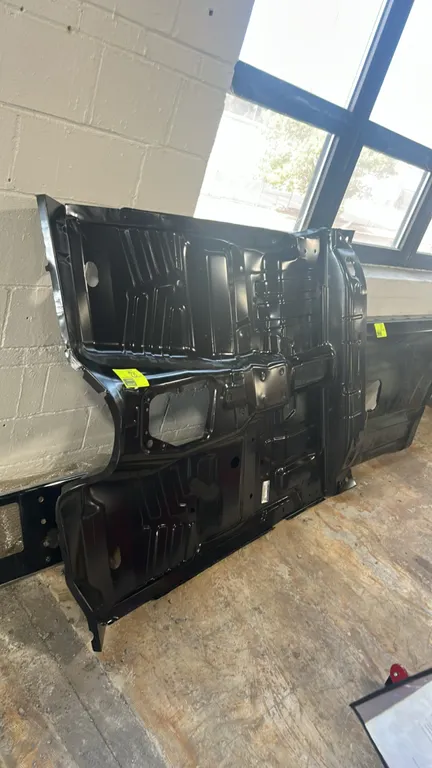 Ford OEM floor pan, part number 7L5Z-131135-A. Stamped steel construction with black protective finish. Features factory structural ribs and pre-forme