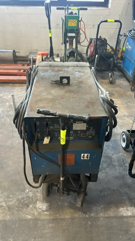 Miller Dialarc HF AC/DC arc welding power source. Features stick electrode holder, ground clamp, welding leads, and top lifting eye. Electrical: 200/2