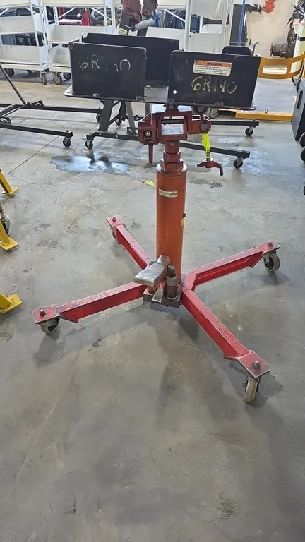 Hydraulic telescopic transmission jack. Features foot-operated hydraulic pump, foot release pedal, and tilt-adjustable saddle with steel transmission