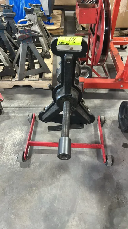 Kiene K-1350 wheel grabber. Features threaded forcing screw, 3-arm puller plate, chain assembly with hook, and hub adapter. Mounted on a mobile caster