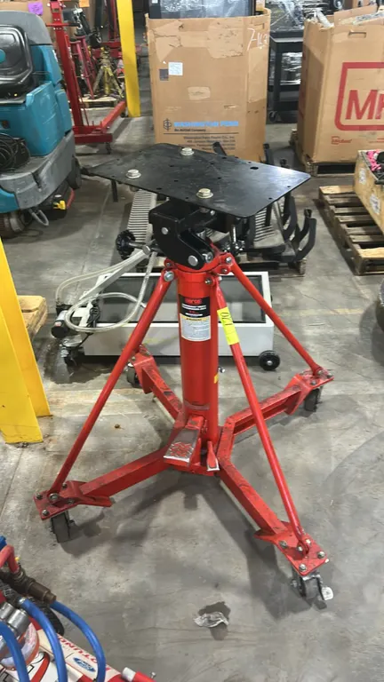 Norco 72700A hydraulic underhoist truck transmission jack. Features 1-ton capacity, adjustable tilting saddle plate, and foot-operated hydraulic pump