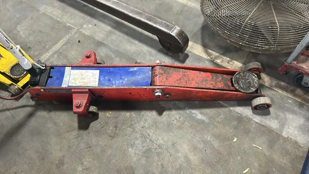 Broadway Ford air/hydraulic floor jack. Features pneumatic operation with manual T-handle control, long-chassis construction, round lifting saddle, fr