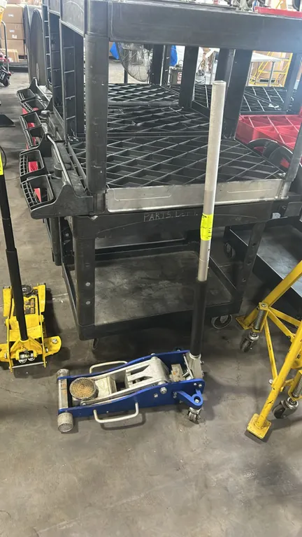 Low-profile aluminum racing floor jack. Features dual-pump hydraulic mechanism, round saddle pad, dual side carrying handles, front wide roller, and r