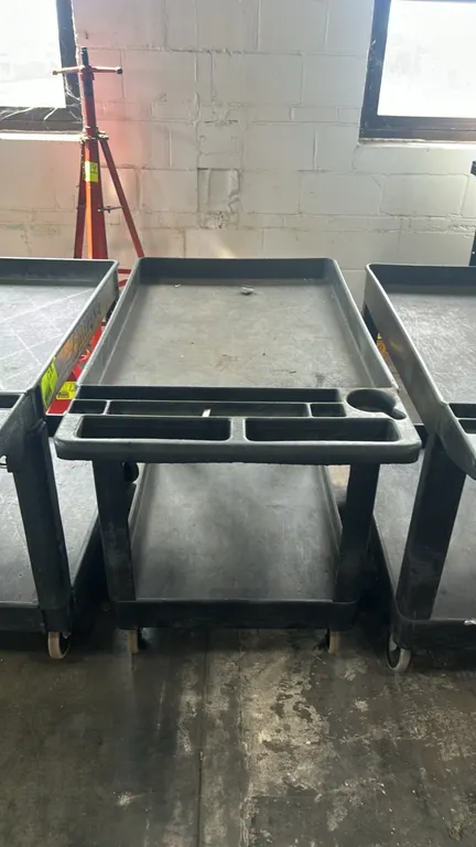 Polypropylene 2-tier utility service cart. Features molded-in handle with integrated tool compartments, cup holder, and deep-lipped shelves. 44"L. Mou