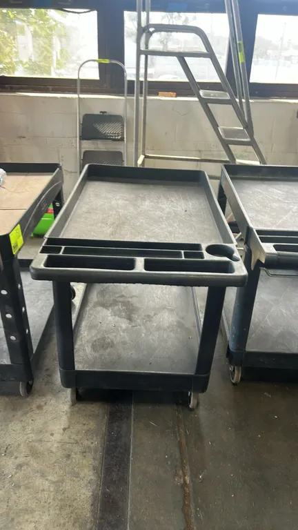 Polyethylene 2-tier utility service cart. Features molded push handle with integrated storage compartments and cup holder and deep-lipped shelves. 44"