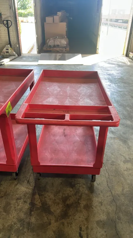 Poly 2-tier utility cart. Features red polyethylene construction, deep lipped tub shelves, and integrated push handle with storage compartments. 44"L.