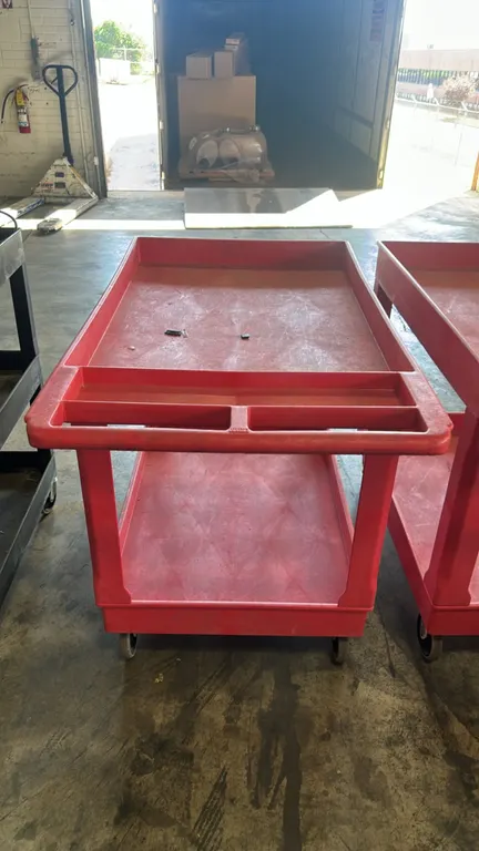 Poly 2-tier utility service cart. Features red molded plastic construction, deep-lipped tub shelves, and integrated push handle with storage compartme