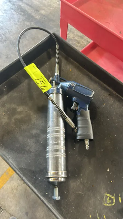 Pneumatic air grease gun. Features a pistol-grip trigger with ergonomic sleeve, bottom quick-connect air inlet, knurled metal grease cartridge barrel,