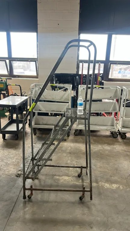 Cotterman steel rolling safety ladder. Features 4 expanded metal treads including top platform, tubular steel safety handrails, and mobile base on spr