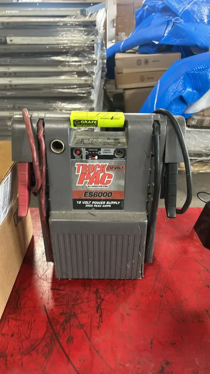 Clore Automotive Truck PAC ES6000 portable battery jump starter. Features integrated jumper cables and clamps, battery status indicator, and 12V DC au