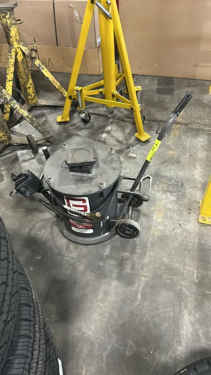 Gray TAJS-3000 truck air jack stand. 20,000 lb capacity. Features pneumatic air hose with control valve, top lifting saddle, side adapter holder, and
