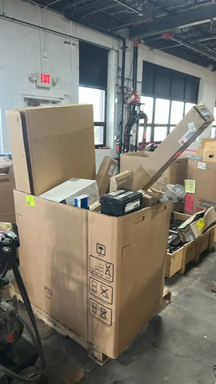 Assorted automotive parts and gaylord pallet contents. Includes Ford OEM tailgate handle (HC3Z-9943400-MB), remanufactured Motorcraft fuel injector (C