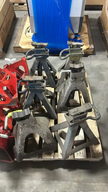 Metal jack stands. Features adjustable ratchet-style support columns with top saddles, locking release handles, and wide-stance steel bases. Pallet an