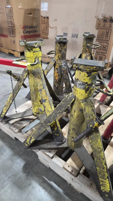 Heavy-duty adjustable jack stands. Features welded steel construction with yellow finish, four-leg support base, top saddles, integrated carry handles